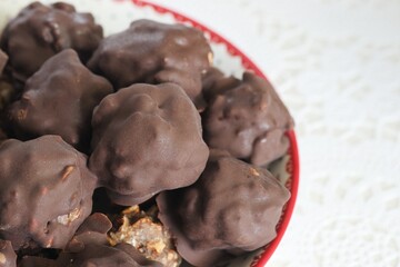 Homemade candy made from nuts and dried fruits. Some are covered in chocolate. They lie on a plate....