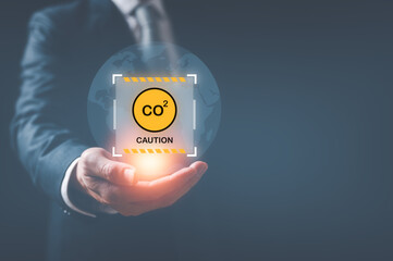 Hand holding virtual glob and caution sign CO2 reducing icon in concept of decrease carbon dioxide...