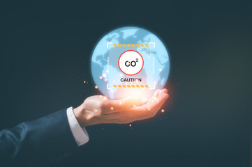 Hand holding virtual glob and caution sign CO2 reducing icon in concept of decrease carbon dioxide emission ,carbon footprint and carbon credit to limit global warming from climate change