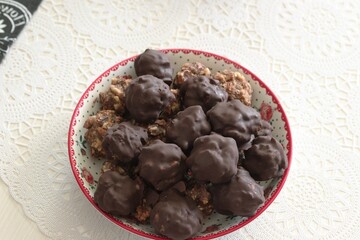 Homemade candy made from nuts and dried fruits. Some are covered in chocolate. They lie on a plate.