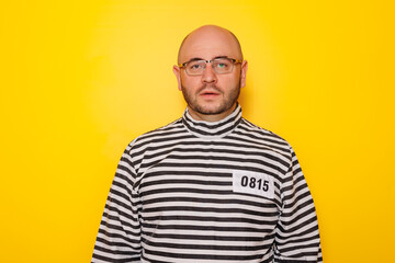 Man wearing prison uniform on yellow colored background