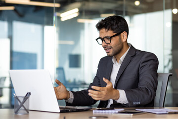 Frustrated and upset hispanic businessman at workplace, man got online rejection error on laptop, unhappy with results inside office in business suit boss.