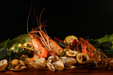 Mixed sea food on the wooden plate with black background.