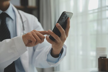 Confident doctor man holding a pill bottle and writing while talking with senior patient and reviewing his medication at office room.