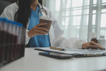 Confident doctor man holding a pill bottle and writing while talking with senior patient and reviewing his medication at office room.
