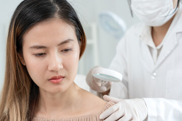Naklejka premium skin problem and beauty of asian girl. specialist of skin use magnifying glass look itchy skin from skin allergic, steroid allergy, sensitive skin, chemical allergy, rash, insect bites, Dermatitis.