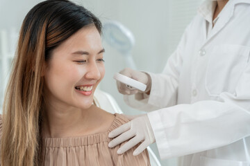 beautiful Asian women smile during receive skin care. specialist of skin use magnifying glass look itchy skin from skin allergic, steroid allergy, sensitive skin, chemical allergy, rash, Dermatitis.