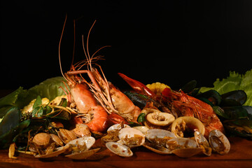 Mixed sea food on the wooden plate with black background.