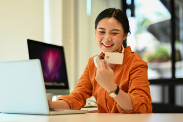 Businesswoman holding credit card for shopping online and happiness moment in modern office.