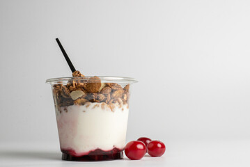 Yogurt with granola flakes and fruits in a plastic cup to go