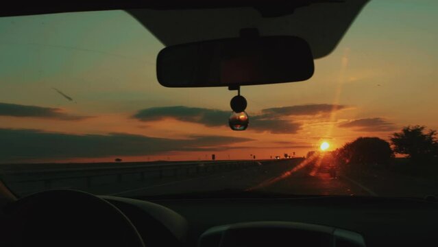 Stunning sunset on horizon through windshield of car. Travel concept