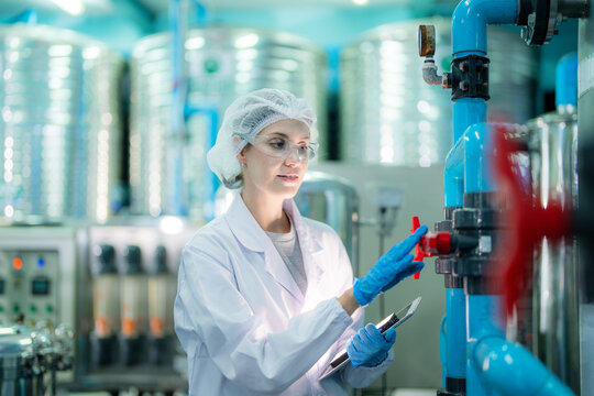 scientist worker checking the quality of Reverse osmosis machine system at the industrial factory. Female worker recording data at the control panel with measure pressure for recycle portable plant.
