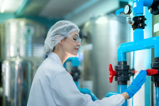 scientist worker checking the quality of Reverse osmosis machine system at the industrial factory. Female worker recording data at the control panel with measure pressure for recycle portable plant.