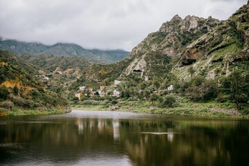 Fototapeta na wymiar Tranquil lake surrounded by rolling mountains, with clouds descending in the distance,La Gomera