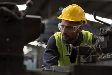 Male engineer worker maintenance lathe machine in industry factory. Male technician worker working and operation machine in plant. Male worker inspecting quality parts of machine