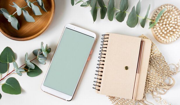 Feminine Smartphone Mockup on White Boho Styled Desk with Mint Notebook and Eucalyptus stock images 