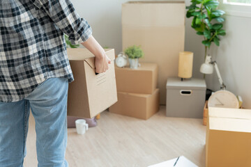 Fototapeta na wymiar Moving house, relocation. Woman hold carton box contain equipment for new condominium, inside the room was a cardboard box containing personal belongings and furniture. move in the apartment