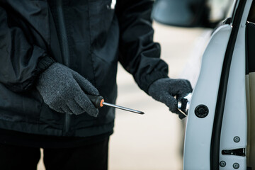 Man dressed in black holding screwdriver to break lock and steal a vehicle on the road, Social...