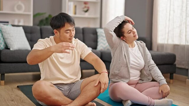 Man and woman couple sitting on floor stretching head at home
