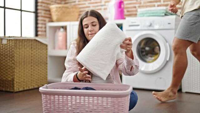 Man and woman couple folding clothes hugging and kissing at laundry room
