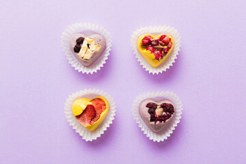 chocolate sweets in the form of a heart with fruits and nuts on a colored background. top view with space for text, holiday concept