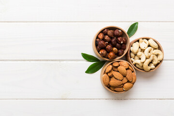 Assortment of nuts in wooden bowl on colored table. Cashew, hazelnuts, walnuts, almonds. Mix of nuts Top view with copy space