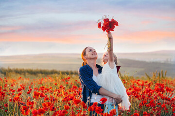 Little girl and her mother with a bouquet of poppies in a field on a summer day