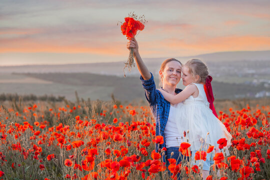 Little girl and her mother with a bouquet of poppies in a field on a summer day