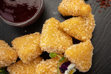 cheesy nuggets on slate plate with sweet sauce. close-up