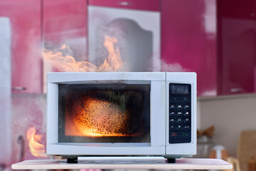 Electric fire from malfunctioning microwave with smoke and open flames in kitchen. - obrazy, fototapety, plakaty