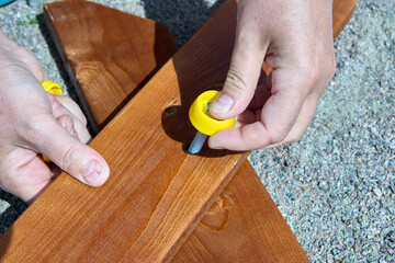 Assembly of outdoor furniture, assembler bolts two boards together.