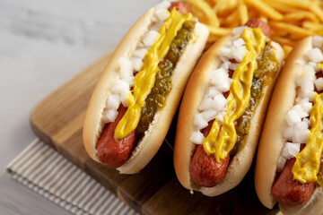 Homemade Deep Fried Hot Dogs with Mustard, Onion and Pickle Relish on a wooden board, side view. Copy space.
