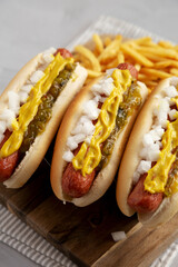 Homemade Deep Fried Hot Dogs with Mustard, Onion and Pickle Relish on a wooden board, side view.