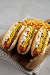 Homemade Deep Fried Hot Dogs with Mustard, Onion and Pickle Relish on a wooden board, side view.