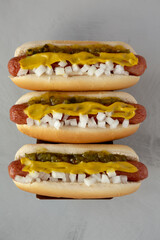 Homemade Deep Fried Hot Dogs with Mustard, Onion and Pickle Relish on a wooden board, top view.