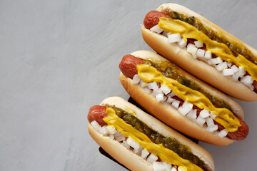 Homemade Deep Fried Hot Dogs with Mustard, Onion and Pickle Relish on a wooden board, top view. Copy space.