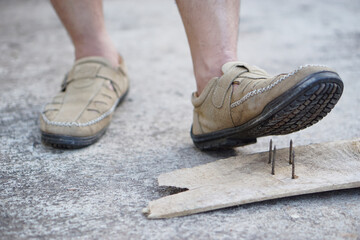 Closeup man wear shoes is stepping on rusty metal nail on wood. Concept, unsafe , risk for dangerous tetanus. Be careful and look around during walking  on the floor or risk places. Accident   