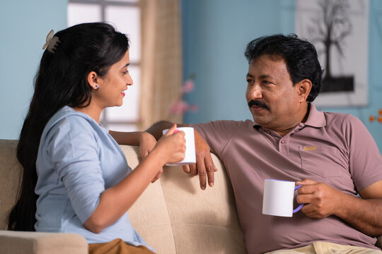 Happy indian daughter with father spending time talking while having tea together at home - concept of leisure time,Joyful Conversation and Companionship