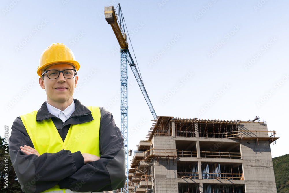 Poster Engineer in a helmet on the background of a building under construction.