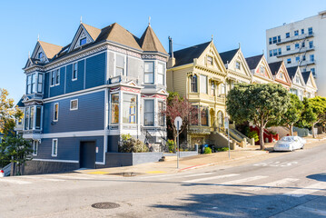 Row of renovated victorian houses along a sloping street in San Francisco on a sunny autumn day