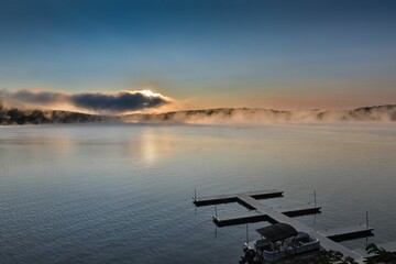 Dramatic sunrise over Deep Creek Lake with an empty dock. Maryland, USA.