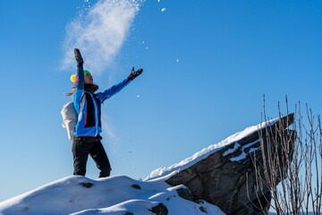 Woman throwing snow in the air on top of the Lion Rock in Slovakia