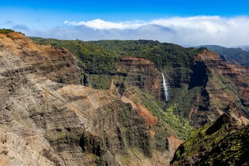 Fototapeta na wymiar Aerial view of a waterfall in green mountains in Waimea Canyon State Park in Kauai County, Hawaii