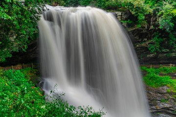 Cascade of water at Dry Falls, North Carolina, flows down the side of a lush, mountainous landscape