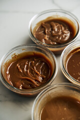 Four Different Salted Caramel sauces in glass bowls on white marble background. Butter, sugar with cream and salt. 