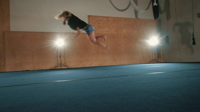 Slow-motion footage of a caucasian female martial artist tricking in a hall