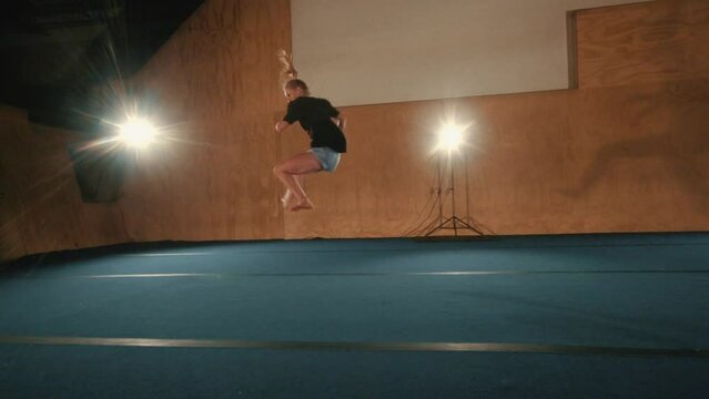 Slow-motion footage of a caucasian female martial artist tricking in a hall
