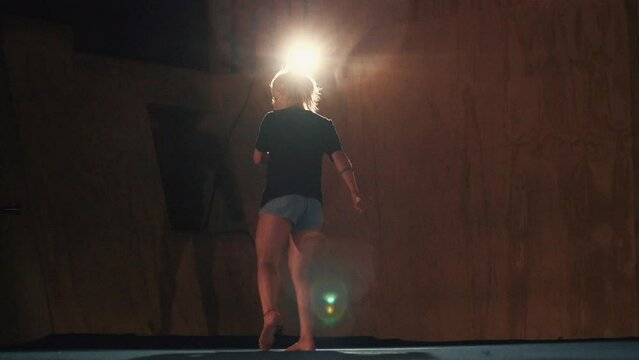 Slow-motion footage of a caucasian female martial artist tricking in a hall