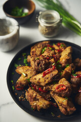 Chinese Salt and Pepper chicken wings. Crispy battered Deep fried chicken wings with vegetables seasoned with salt and pepper and then quickly sauteed with onions, garlic and chilies.