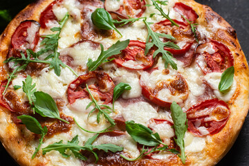 Pizza with ham,tomatoes and mozzarella on a dark background